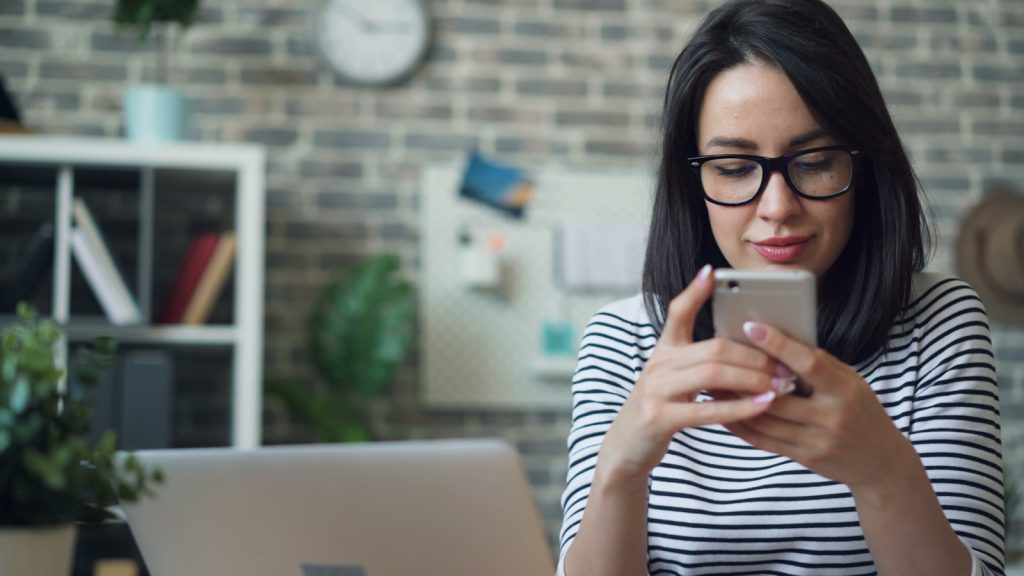 a woman wearing glasses looking at her cell phone