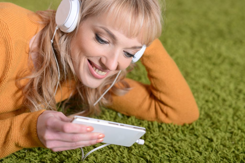 Jak słuchać audiobooka na telefonie? Najlepsze aplikacje i formaty plików Portret pięknej kobiety słuchającej muzyki