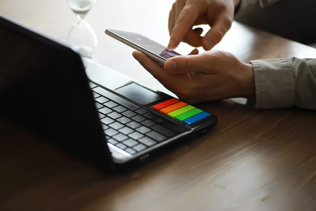 Jak wyłączyć kolory w telefonie? Tryb skali szarości i cyfrowy detoks Ręce używające laptopa i telefonu do zakupów online zbliżą czysty obraz przed oknem w miękkim świetle