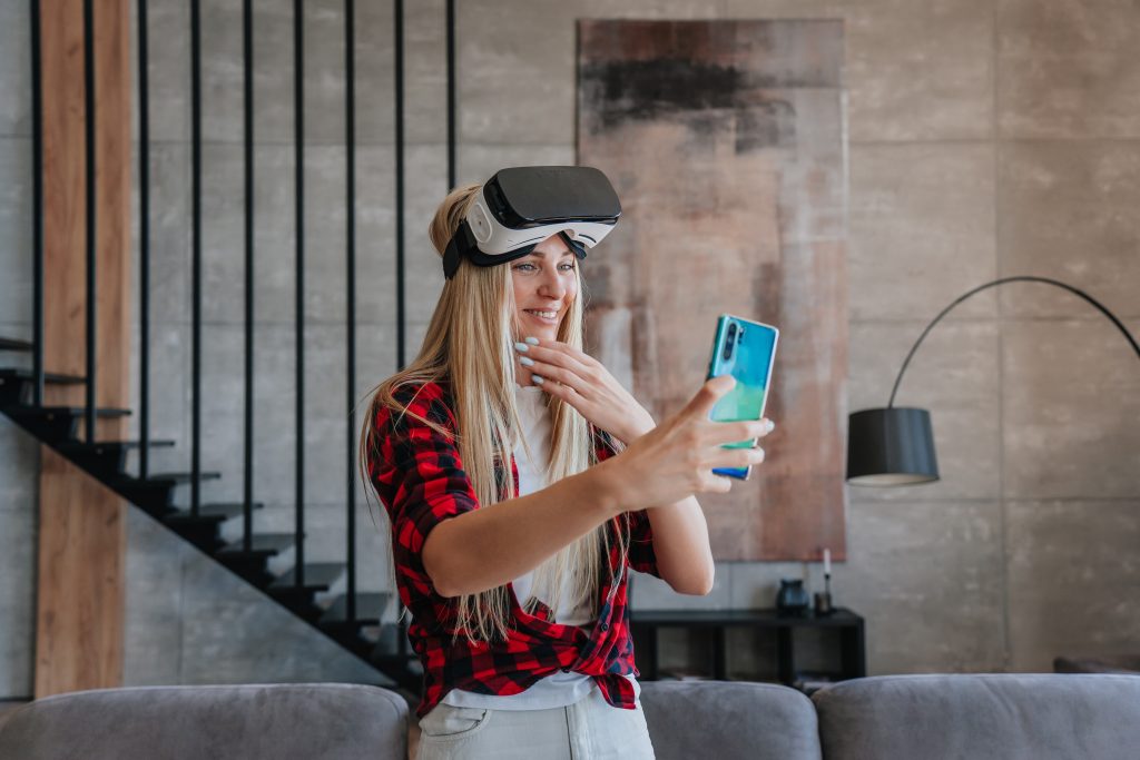 Atrakcyjna młoda blondynka rasy kaukaskiej w kraciastej koszuli i białych spodniach z okularami vr na głowie sprawia, że rozmowa wideo uśmiecha się w domu Rzeczywistość wirtualna nowoczesne technologie Zajęcia rekreacyjne