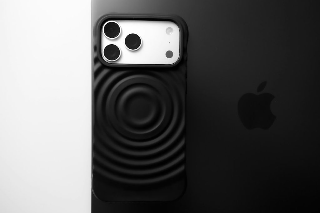 Minimalistyczne czy pancerne? Jakie etui do iPhone’a 17 i 17 Pro wybrać Black smartphone with textured case and apple logo.