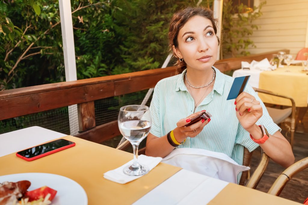 Jak zmienić limit w IKO na telefonie? Zarządzanie kwotami transakcji Kobieta płaci kartą kredytową po kolacji w kawiarni Nowoczesne technologie transakcyjne i banki